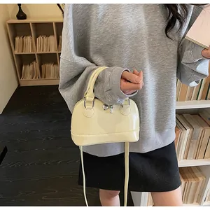 Détail d'un sac crème avec breloques cœur et clé avec bandoulière réglable chic