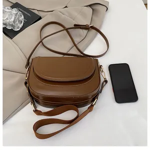 Deep brown saddle bag shown with interchangeable leather and wide canvas straps