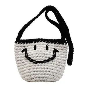 Minimalist hand-woven bucket bag with black smile face design and contrasting shoulder strap
