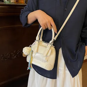 Chic cream shell-shaped handbag with adjustable strap and cute charm in lifestyle scene