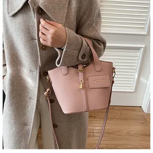 Sac en cuir grainé rose avec ferrures dorées et plaque logo porté par un modèle
