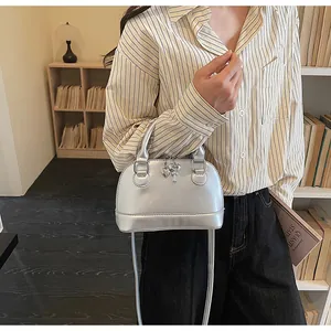 Détail du sac coquille argenté montrant la texture PU et le pendentif clé en cœur