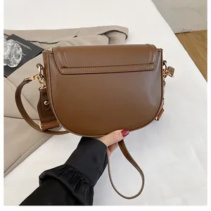 Detail view of a brown saddle bag with premium leather texture and metallic hardware