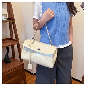 Detail of a creamy white crocodile pattern shoulder bag featuring a silver metal twist lock
