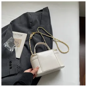 Detailed macro view of the white structured chain bag showing gold metal leather strap