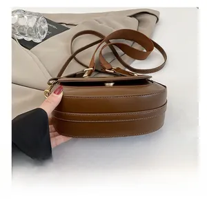 Close-up of brown saddle bag showing smooth leather texture and gold hardware detail