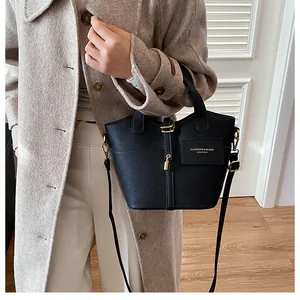 Détail du sac seau noir en cuir grainé avec fermoir doré et lettrage de mode élégant