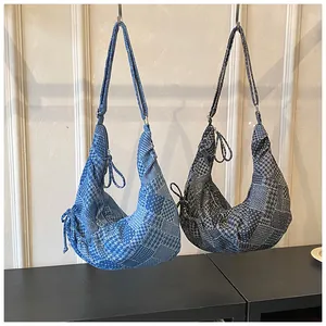 Detail of crescent denim crossbody bags featuring patchwork patterns and adjustable straps