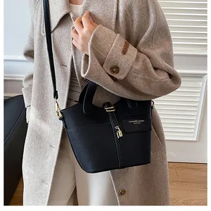 Détail du sac seau en cuir grainé noir avec fermoir doré et lettrage de mode imprimé