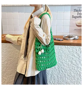 Close-up of green hand-woven hollow knit tote bag featuring white tulip charms