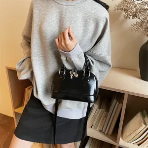Sac à main noir classique style coquillage avec breloques dans un décor élégant