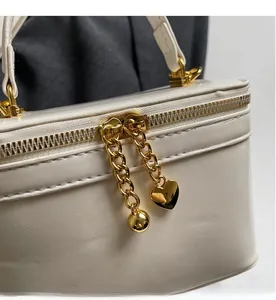 Detail of white PU leather bag featuring gold double zippers and heart-shaped chain pulls
