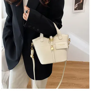 Détail du sac seau en cuir grainé crème avec fermoir doré et lettrage de mode chic
