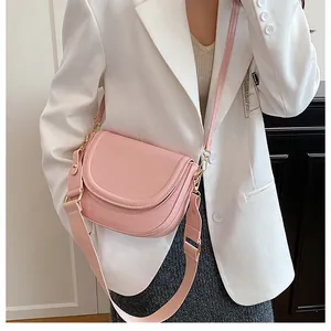 Detail showing pink saddle bag with adjustable wide fabric strap and golden buckle hardware