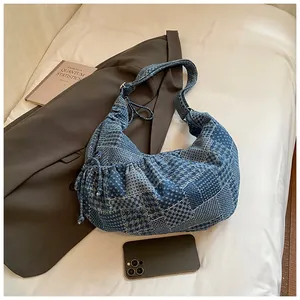 Detail of blue denim patchwork crescent bag with houndstooth pattern and drawstring side