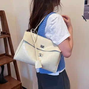 Chic cream crocodile pattern shoulder bag with dual silver clasps shown on model