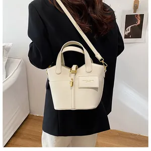Détail du sac crème en cuir grainé avec finitions dorées et lettrage élégant