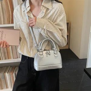 Sac à main argenté forme coquillage avec pendentif cœur et bandoulière sur mannequin