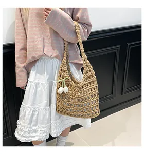 Detail of woven straw tote bag with white tulip charm and ribbon on model's shoulder