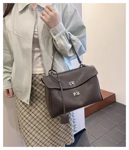 Détail de la texture en cuir plissé et des fermoirs tournants argentés du sac à bandoulière