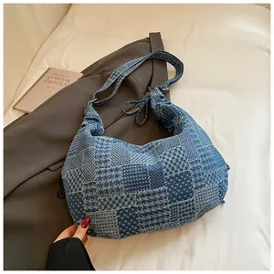Detail of blue denim hobo bag featuring retro patchwork textures and wide shoulder strap