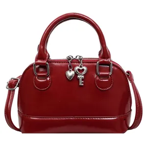 Sac à main coquillage rouge foncé en cuir verni avec charme cœur et bandoulière réglable
