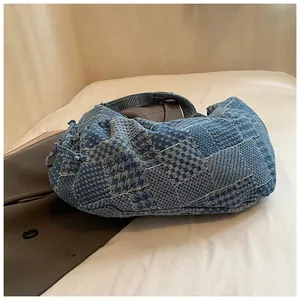 Detail of patchwork denim crescent bag with houndstooth pattern and drawstring side