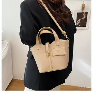 Détail du sac seau en cuir grainé abricot avec fermoir doré et texte embossé élégant