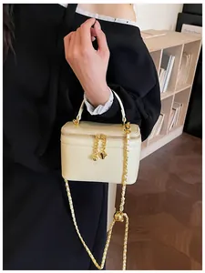 Detail of cream leather box bag featuring gold heart pendant and metal ball chain