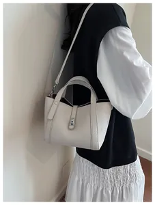Détail du sac seau en cuir grainé blanc avec doubles poignées et fermoir en métal