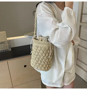 Detail of straw woven bucket bag with drawstring liner on female model for beach holiday
