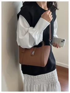 Sac à main marron en cuir grainé porté par un mannequin avec bandoulière réglable