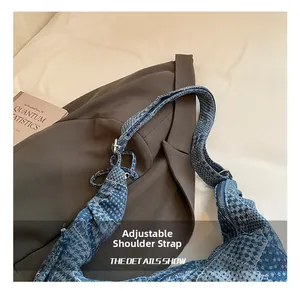 Detail of blue checkered denim crescent bag featuring adjustable strap and zipper closure