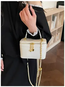 Detailed view of a white box bag featuring a gold chain strap and heart charm pendant