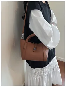 Vue détaillée d'un sac seau marron avec motif litchi porté par un mannequin femme