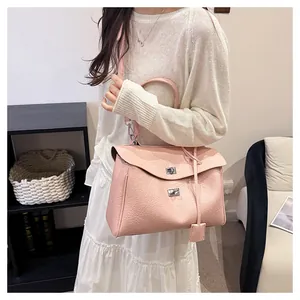 Détail du sac à main en cuir rose clair avec boucles argentées sur robe blanche