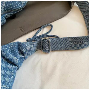 Detail of adjustable strap with silver buckle on blue houndstooth denim crescent bag