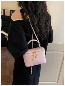 Detail of a pink vanity bag with gold chain strap and heart charm on the zipper