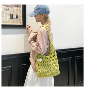Detail of hand-woven hollow knit tote bag with tulip pendant on a female model