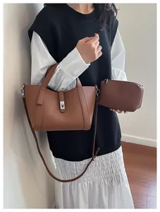 Détail d'un ensemble de sacs en cuir marron grainé avec fermoir rotatif et bandoulière réglable