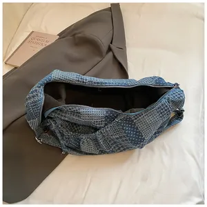 Detailed top view of denim crescent bag with blue checkerboard pattern and silver zipper