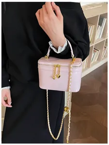 Detail of pink chain box bag featuring heart charms and gold-tone metal hardware