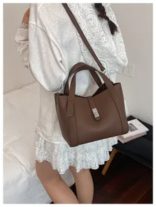 Détail d'un sac à main en cuir marron à motif litchi porté par un mannequin en style décontracté