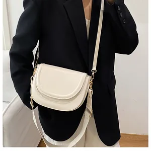 Close-up of off-white saddle bag with golden metal hardware and dual detachable straps
