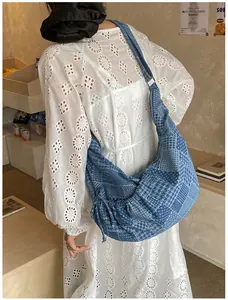 Detail of checkered denim hobo bag featuring drawstring sides and a wide shoulder strap