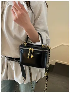 Chic black crossbody bag with gold chain strap and heart charm worn by a model