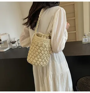 Detail of handmade woven beige bucket bag with popcorn texture and drawstring closure