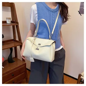 Détail du sac à main en cuir crème avec texture litchi et fermoirs rotatifs argentés