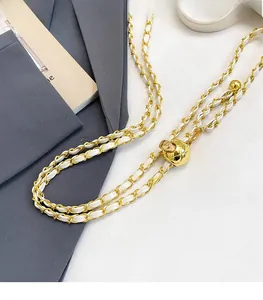Détail de la boucle boule dorée réglable et de la bandoulière chaîne en cuir blanc