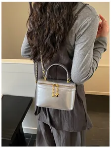 Detail of silver crossbody bag with golden heart charms and chain strap on a female model